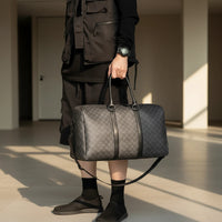 Person holding a gray patterned duffel bag with a neutral background