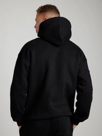 Person wearing a black hoodie from behind on a plain background