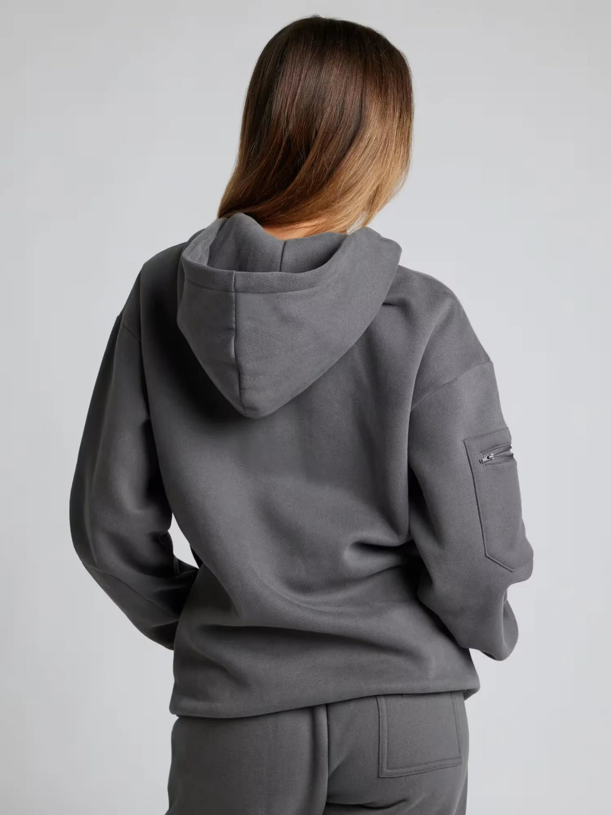Person wearing a gray hoodie and pants on a plain background