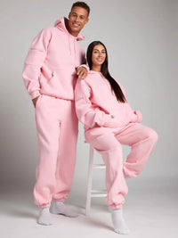 Two people wearing matching pink outfits on a plain background