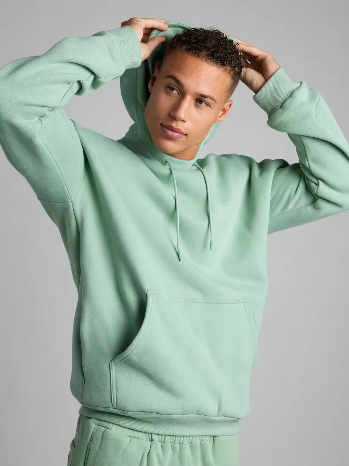 Person wearing a light green hoodie against a gray background