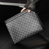 Person holding a black and gray patterned clutch bag on a dark background