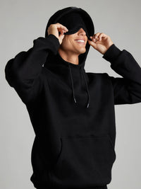 Person wearing a black hoodie with a plain background