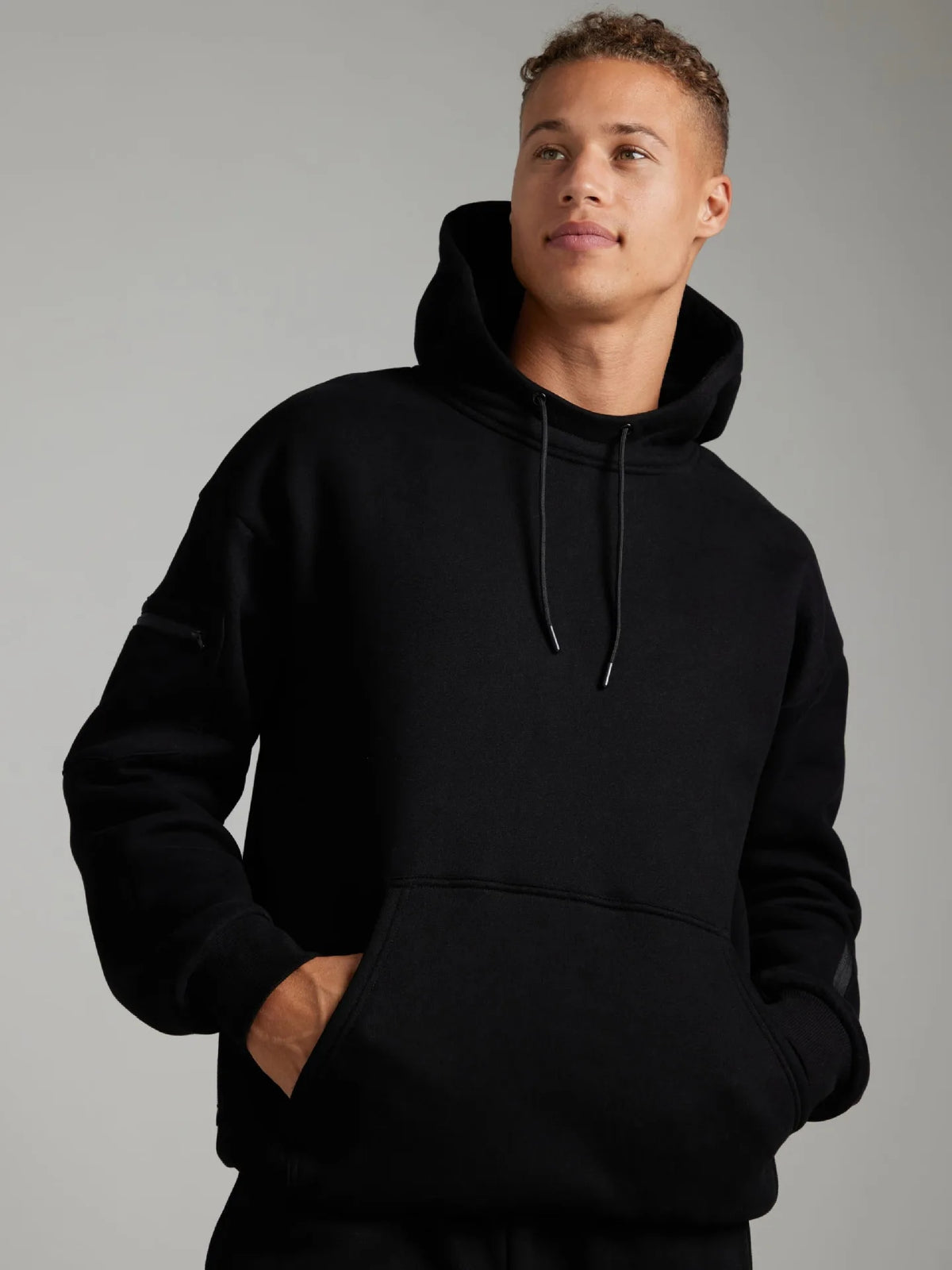 Person wearing a black hoodie against a gray background