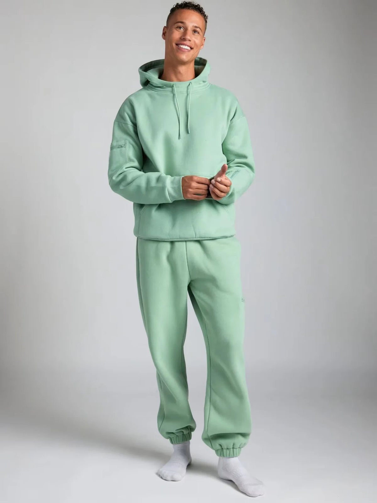 Person wearing a light green tracksuit against a plain background