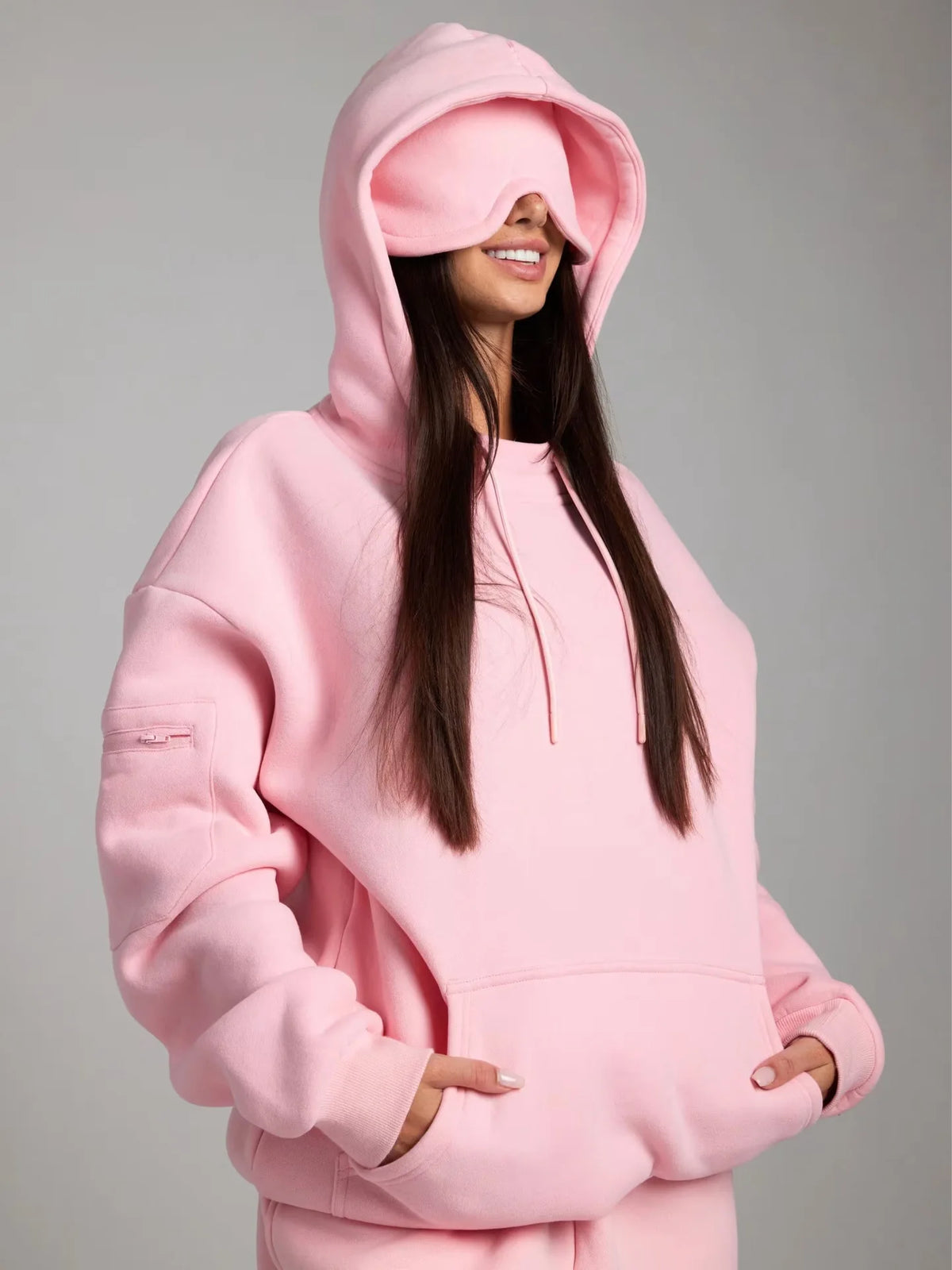 Person wearing a pink hoodie on a gray background