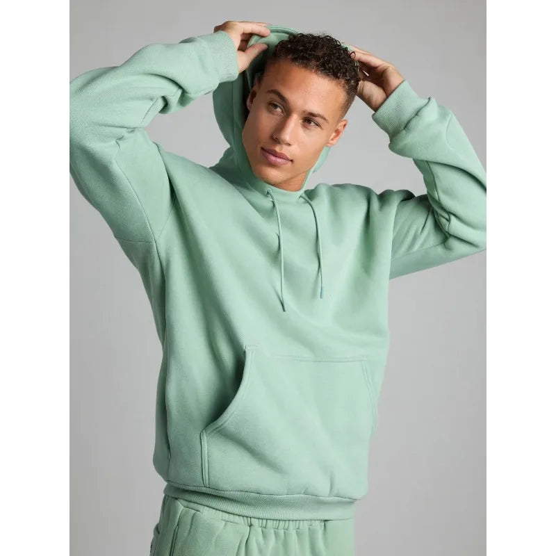 Person wearing a light green hoodie against a gray background