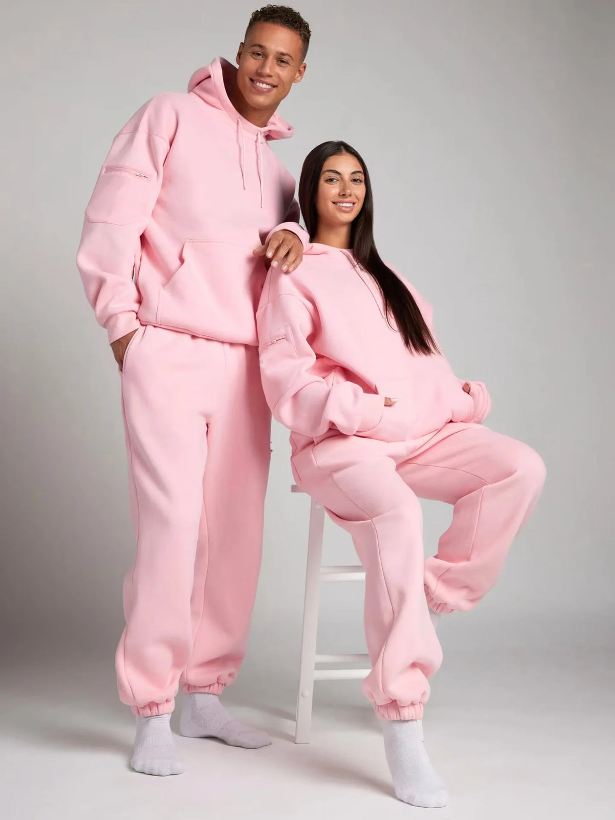 Two people wearing matching pink outfits on a plain background
